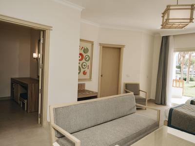 Helles Hotelzimmer mit grauem Sofa, Bildern an der Wand und blick auf Terrasse.