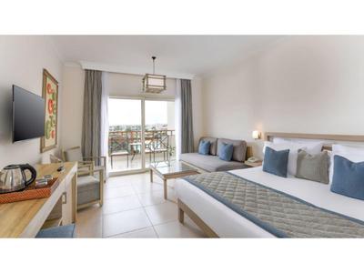 Modern eingerichtetes Hotelzimmer mit Doppelbett, Balkon und Sitzbereich in neutralen Tönen.