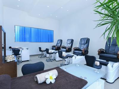 Moderne wellnessruimte met massagestoelen en behandelbedden in een lichte kamer.