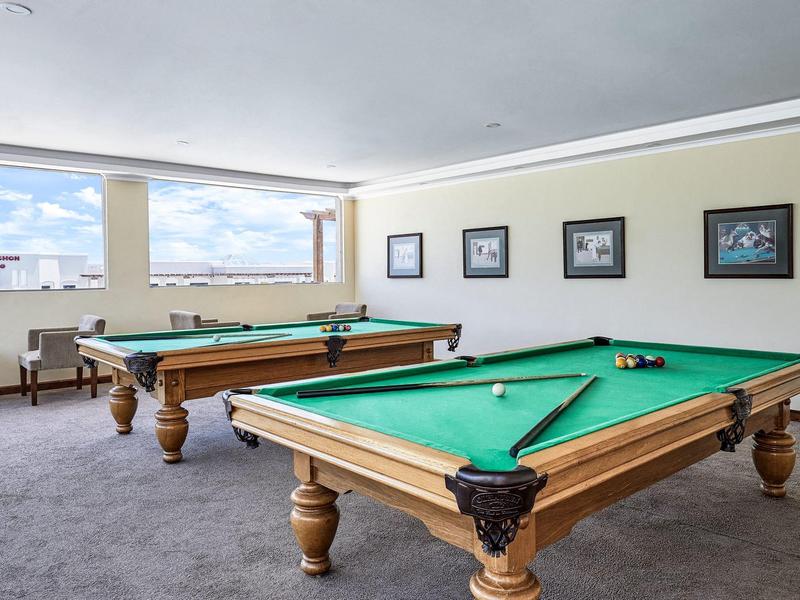 Světelná kulečníková místnost se dvěma stoly s koulemi a tágy.