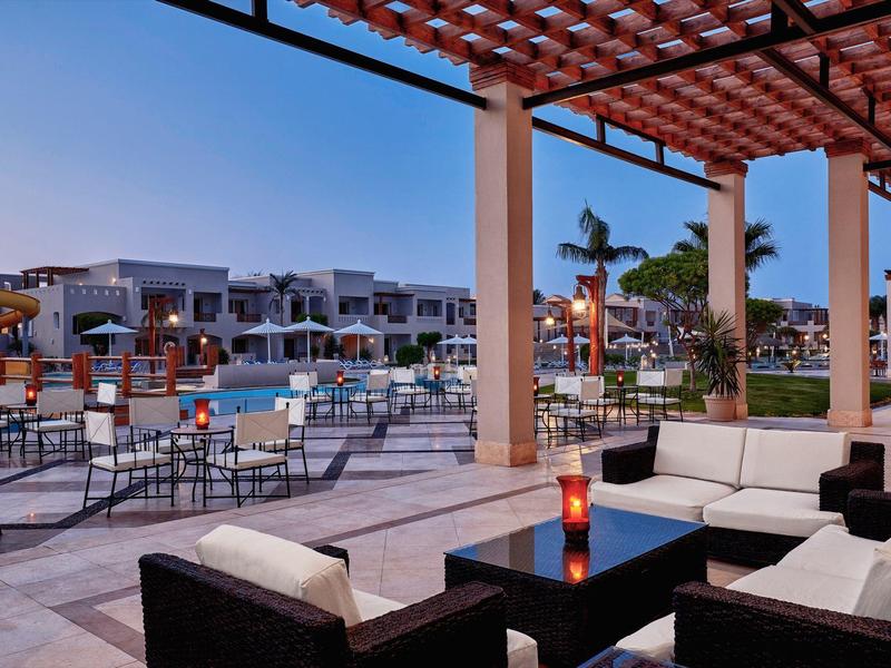 Hotelová terasa s pohovkami a bazénem za soumraku, moderní a klidná atmosféra.