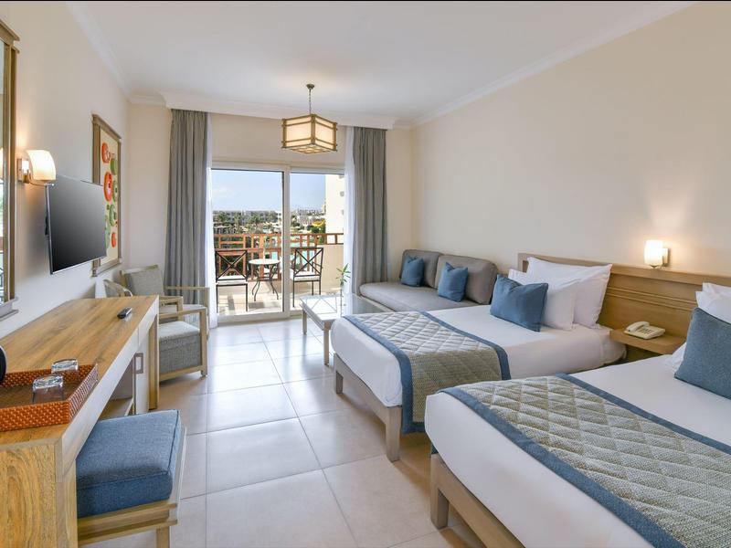 Světle zařízený hotelový pokoj se dvěma postelemi, terasou a moderním nábytkem.