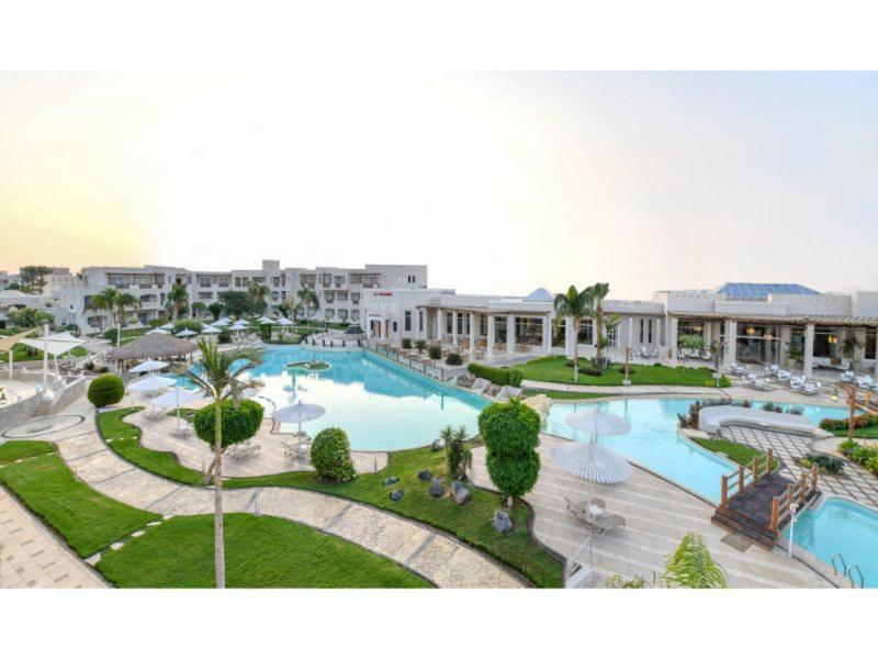 Hotelový komplex s velkými bazény, upravenými trávníky a moderními budovami v pozadí.