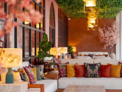 Ein gemütlicher Hotel-Loungebereich mit weißen Sofas, bunten Kissen und warmem Licht.