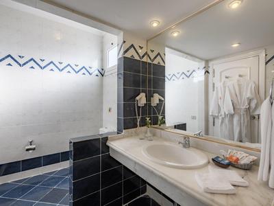 Moderne badkamer met grote douche, wastafel, spiegel en handdoeken.