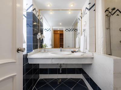 Moderne badkamer met grote spiegel, wastafel en zwart betegelde wand.