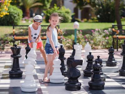 Kinderen spelen buiten op een groot schaakbord bij een vakantiebestemming.