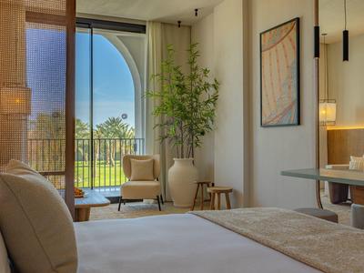 Licht ingericht hotelkamer met groot raam en uitzicht op tuin