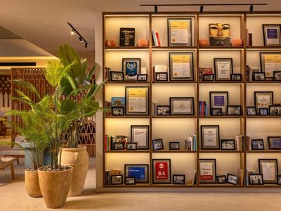 Moderne hotel lobby met een wandrek, decoratieve afbeeldingen en grote plantenpotten.