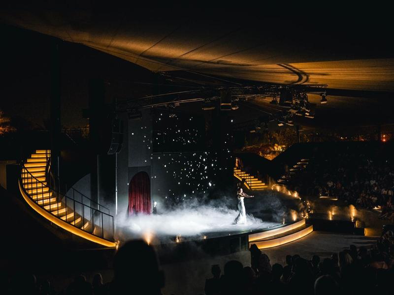 Podium met theaterverlichting en nefeffecten voor publiek in donkere zaal