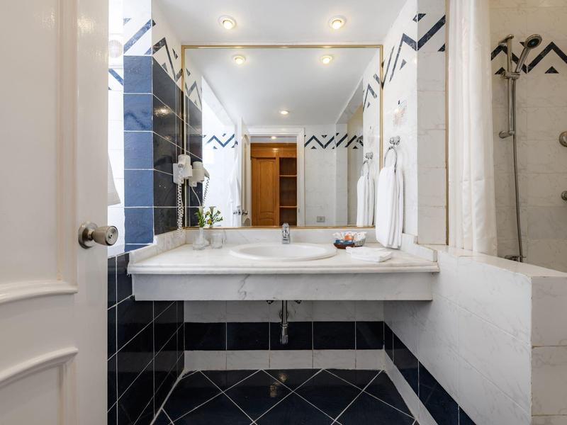 Moderne badkamer met grote spiegel, wastafel en zwart betegelde wand.