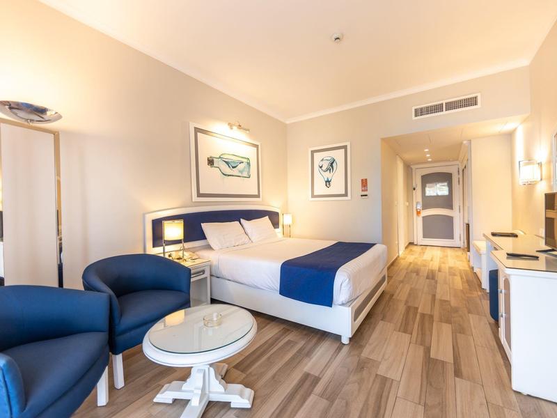 Modern hotelkamer met tweepersoonsbed, zithoek en houten vloer.