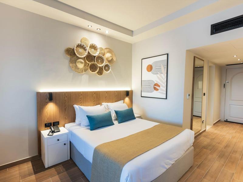 Modern hotelkamer met groot bed, bedlampjes en wanddecoratie.