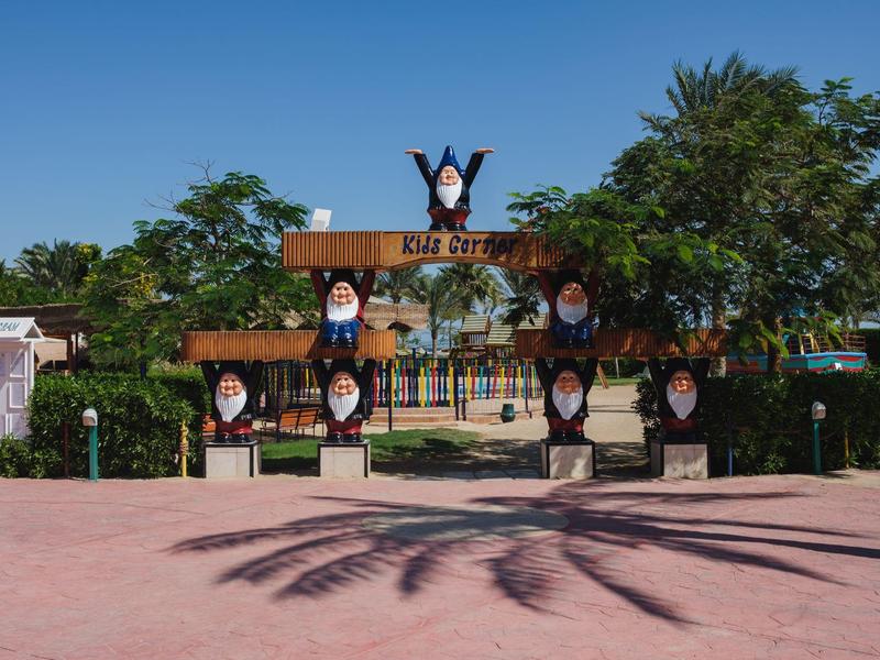Entree met vogelbeelden en palmbomen in een zonnig pretpark.