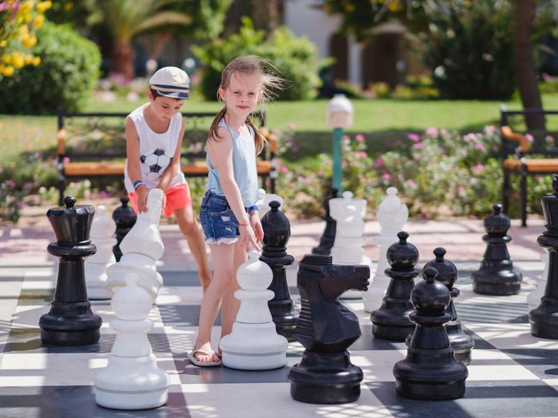 Kinderen spelen buiten op een groot schaakbord bij een vakantiebestemming.