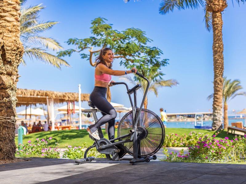 Vrouw die buiten op een hometrainer traint in een tropische vakantiesfeer.