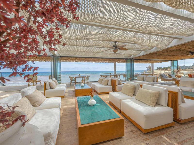 Open lounge met comfortabele banken en uitzicht op zee onder een beschut dak.