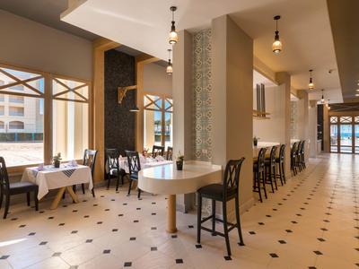 Elegantes Hotelrestaurant mit weißen Tischen, dunklen Stühlen und großen Fenstern.