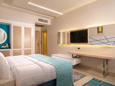 Nowoczesny pokój hotelowy z podwójnym łóżkiem, biurkiem i dużym lustrem.