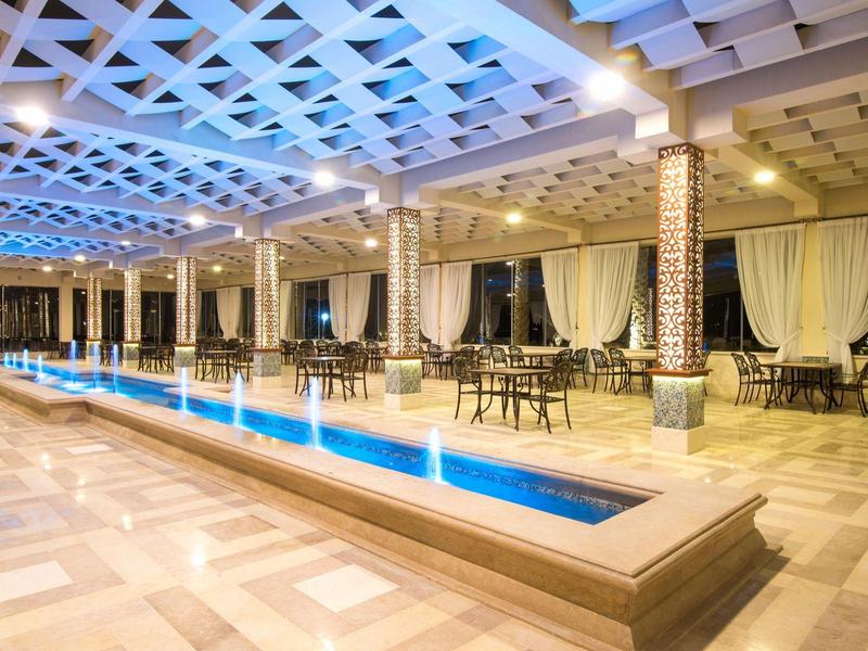Jasny salon hotelowy z elegancką fontanną i miejscami do siedzenia pod futurystycznym sufitem.