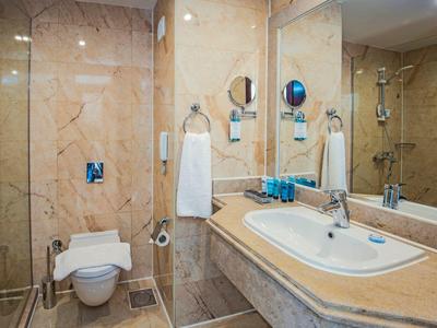 Baño de hotel con paredes de mármol, lavabo, inodoro y toallas.