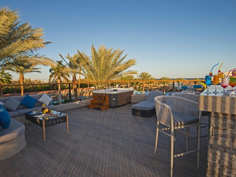 Terraza exterior acogedora con asientos y palmeras a la luz del día.