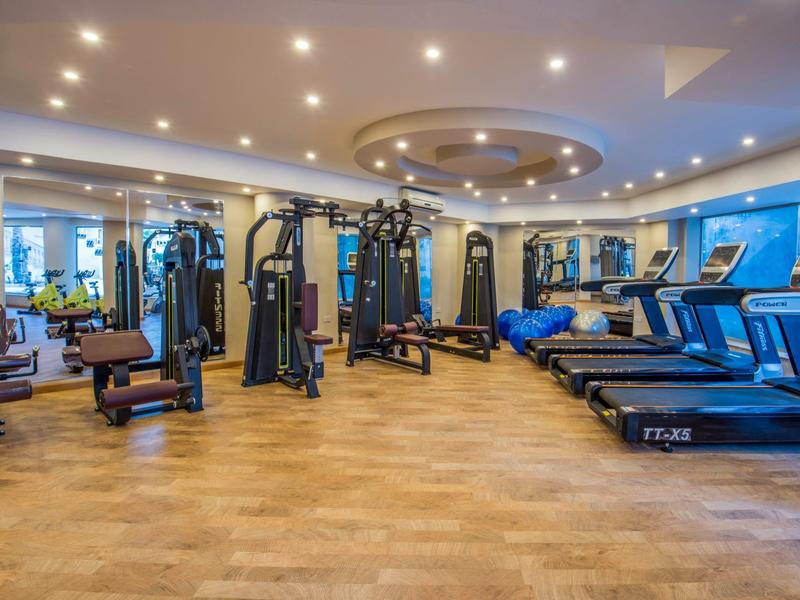 Gimnasio moderno con equipos de entrenamiento y cintas de correr en un espacio amplio y luminoso.