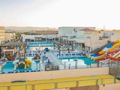 Großer Hotelpoolbereich mit Wasserrutschen und mehreren Schwimmbecken in sonniger Umgebung.