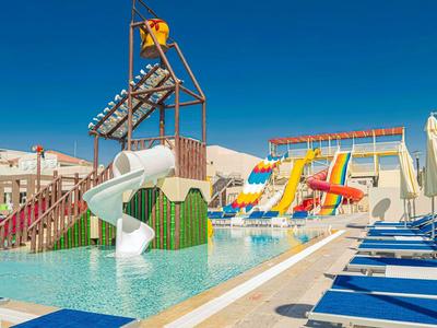 Wasserpark mit bunten Rutschen, Swimmingpool, blauen Liegestühlen und klarem Himmel.