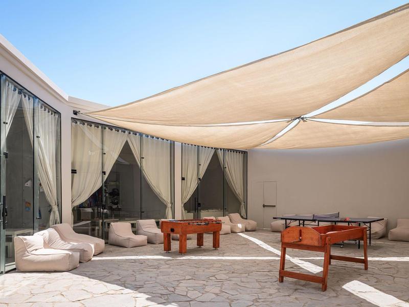 Sonnendurchfluteter Außenbereich mit Sitzsäcken, Tischfußball und Schattensegeln.