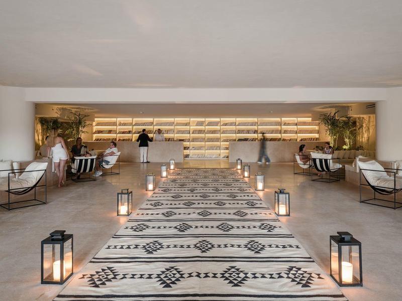 Weißer Teppich mit Muster, Laternen, Sitzbänke, helle offene Empfangshalle mit warmem Licht.