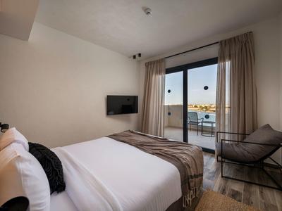 Modernes Hotelzimmer mit Doppelbett, Fenster mit Blick auf das Wasser und einem Sessel.