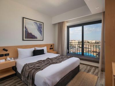 Chambre d'hôtel moderne avec lit double, balcon et vue sur la ville.