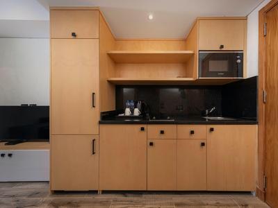 Kleine moderne Küchenzeile mit Holzschränken, Mikrowelle und schwarzen Arbeitsflächen.