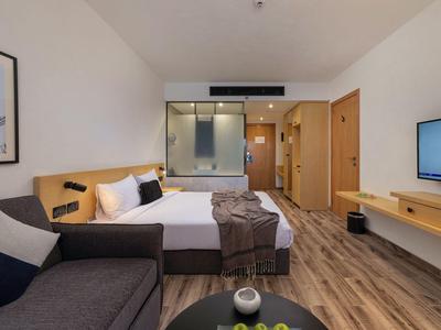 Modernes Hotelzimmer mit Doppelbett, Sofa, Flachbildschirm und Holzboden.