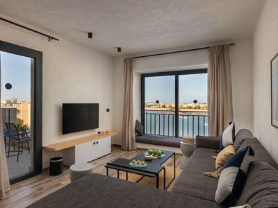 Modern eingerichtetes Wohnzimmer mit Sofa, großem Fenster und Fernseher in einer Ferienwohnung.