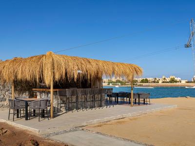 Bar de plage avec toit de chaume à côté d'eau calme sous un ciel clair