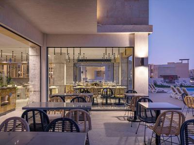 Espace extérieur moderne d'hôtel avec tables et chaises au crépuscule.