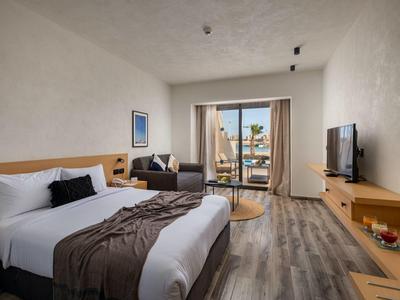 Modernes Hotelzimmer mit Doppelbett, Sofa und Balkon mit Meerblick.