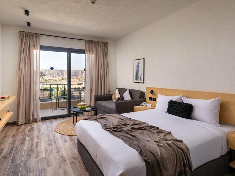 Modernes Hotelzimmer mit großem Bett, Balkon und Blick auf die Stadt.