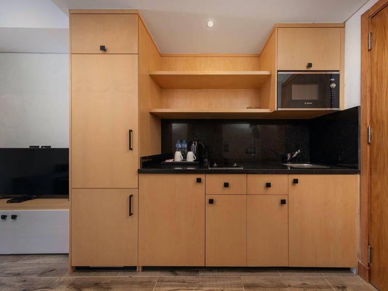 Kleine moderne Küchenzeile mit Holzschränken, Mikrowelle und schwarzen Arbeitsflächen.