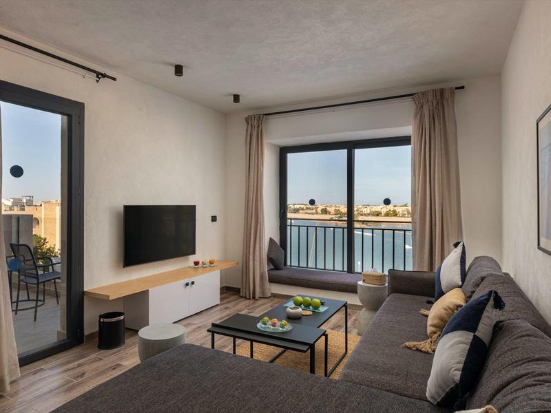 Modern eingerichtetes Wohnzimmer mit Sofa, großem Fenster und Fernseher in einer Ferienwohnung.