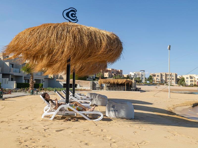 Strand mit Sonnenschirmen aus Stroh und Liegestühlen bei einem Hotel am Meer