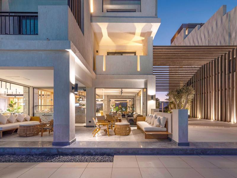 Modernes Hotel mit offener Lobby, Sitzbereichen und warmem Beleuchtungskonzept bei Dämmerung.