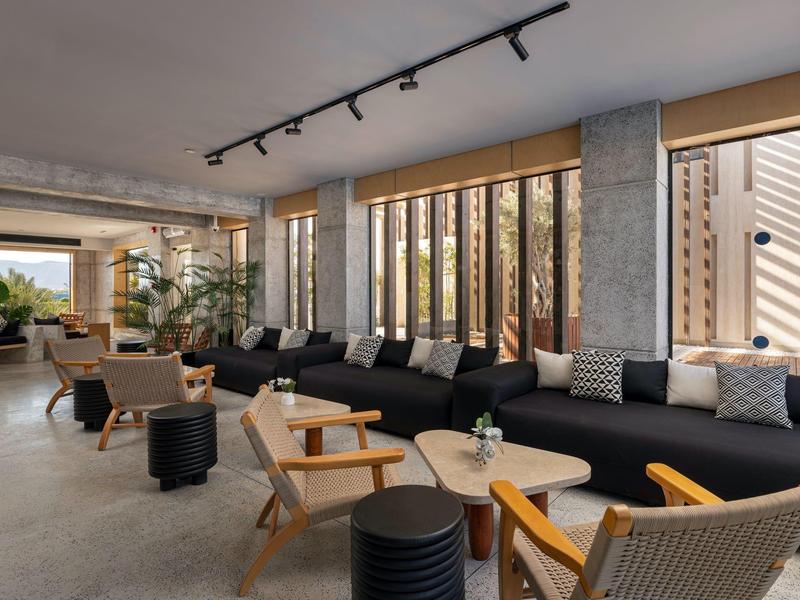 Modern eingerichteter Hotel-Lounge-Bereich mit bequemen Sesseln und Sofas bei Tageslicht.