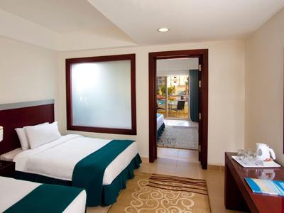 Hotel room with two single beds, desk, carpet, and view into the bathroom.