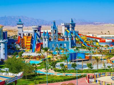 Barevný vodní park s tobogány a hradním pozadím v slunné pouštní krajině