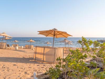 Písečná pláž s několika slunečníky a výhledem na klidné moře