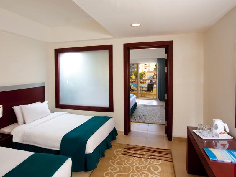 Hotel room with two single beds, desk, carpet, and view into the bathroom.