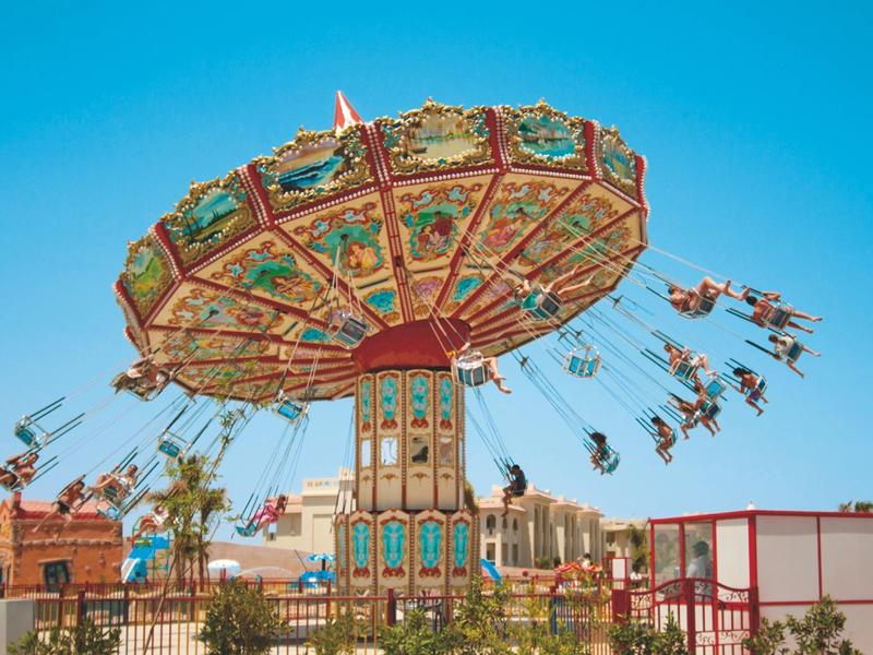 Colorful swinging swing ride at a sunny amusement park.